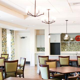 A modern dining area with elegant lighting, tables, and chairs.