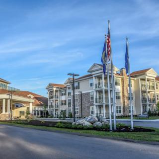 A modern building with multiple flags in the foreground under a blue sky.