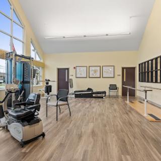A spacious and well-lit therapy room equipped with exercise machines and rehabilitation tools.