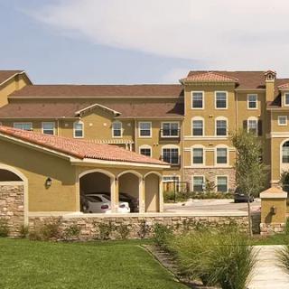 A suburban apartment complex with multiple stories and a landscaped foreground.
