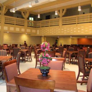 A spacious dining hall with wooden tables, chairs, and floral decorations.