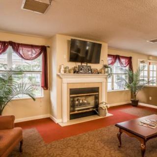 A cozy living room with a fireplace and mounted television, featuring large windows and comfortable seating.