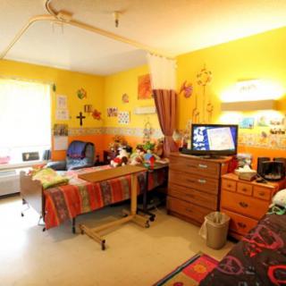 A cozy and brightly colored bedroom featuring vibrant yellow walls, a television, and various decorative items.