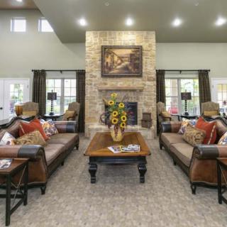 A spacious living room featuring a central brick fireplace, surrounded by elegant sofas and a coffee table adorned with sunflowers.