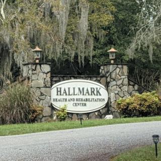 Entrance sign for Hallmark Health and Rehabilitation Center, surrounded by lush greenery.