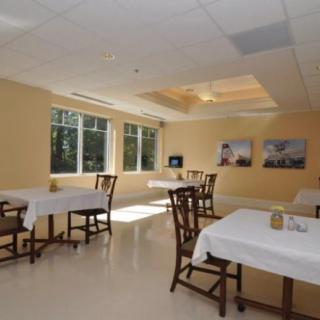 A bright and airy dining area with neatly arranged tables and chairs, illuminated by natural light from large windows.