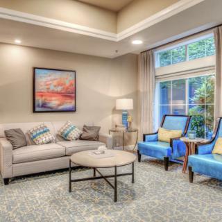 A cozy living room with a sofa, armchairs, coffee table, and large window, featuring neutral tones and stylish decor.