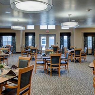 A spacious and elegantly designed dining room with neatly arranged tables and chairs, featuring large windows and modern lighting fixtures.