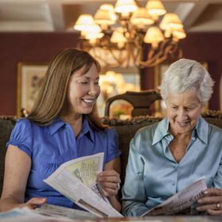 Two women enjoying reading together in a cozy room.