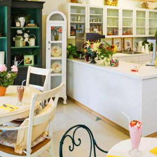 A quaint cafe interior with vintage decor, showcasing tables, chairs, and colorful floral arrangements.