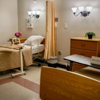 A hospital room with a bed, curtain, and various pieces of furniture.