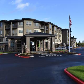 A modern residential apartment building with a driveway and well-kept landscaping.