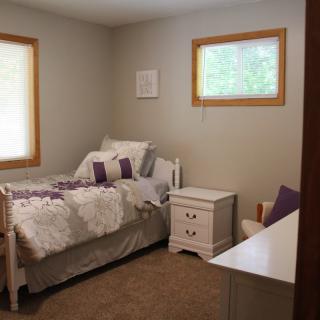 A cozy bedroom with a single bed and neutral decor.