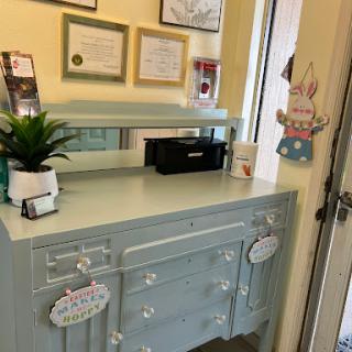 A charming blue desk set up with certificates, a plant, and office supplies.