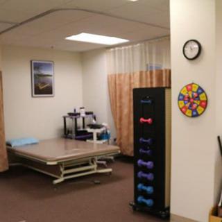 A physical therapy room equipped with exercise tools and a treatment table.