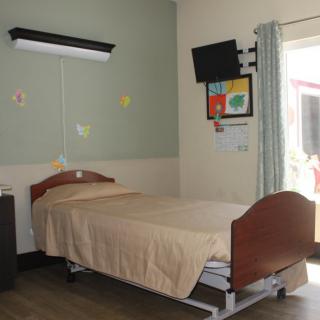 A hospital room with a single bed and medical equipment.