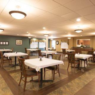A cozy dining area with neatly arranged tables and chairs, warmly lit and inviting.