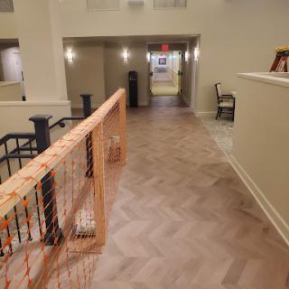 A well-lit interior hallway featuring herringbone flooring and modern decor.
