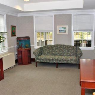 A tidy office space with a sofa, desk, and fish tank.