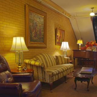 A cozy living room with a striped sofa, multiple lamps, and decorative paintings on the wall.
