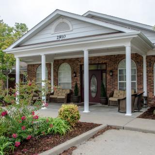 A charming house with a front porch supported by white columns and surrounded by a well-maintained garden.