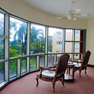 A cozy seating area with large glass windows overlooking lush palm trees.