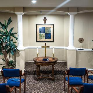 A serene chapel setting with a cross, comfortable seating, and decorative elements, ideal for reflection and prayer.