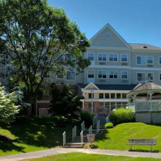 A large building surrounded by lush greenery and a well-maintained lawn on a sunny day.