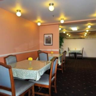 A cozy restaurant dining area with tables and chairs, softly lit by overhead lights.