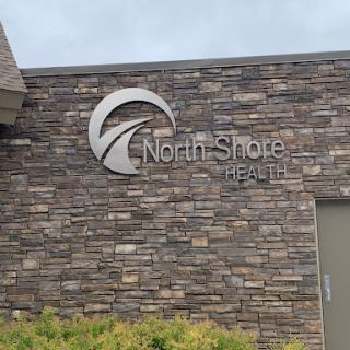Exterior view of the North Shore Health facility with a stone wall design.