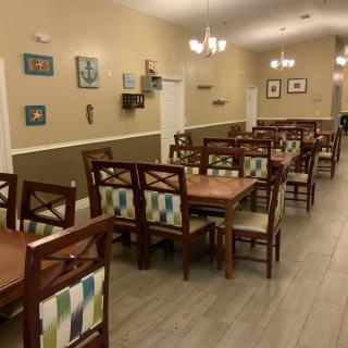 A well-arranged dining room featuring wooden tables and chairs, adorned with patterned cushions, under warm lighting and decorated walls.