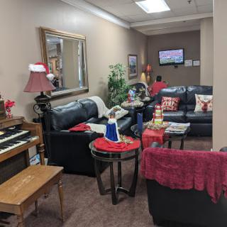 A cozy living room setting featuring comfortable black leather sofas, a piano, and decorative elements that create a warm atmosphere.