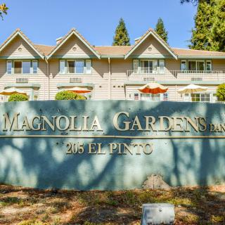 A residential apartment complex with a sign reading 'Magnolia Gardens, 25 El Pinto'.