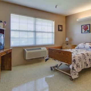 A hospital room with a single bed, television, and window providing natural light.
