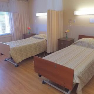 A well-lit hospital room featuring two twin beds separated by curtains, designed for patient comfort.