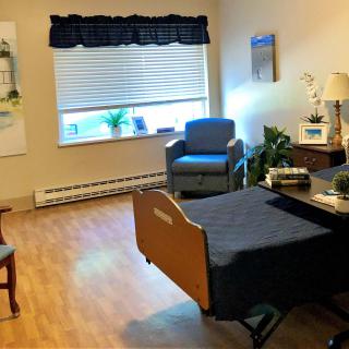 A tidy and well-lit room with a hospital bed, chairs, and a window letting in natural light.