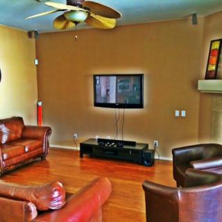 A cozy living room with leather furniture and a wall-mounted television.