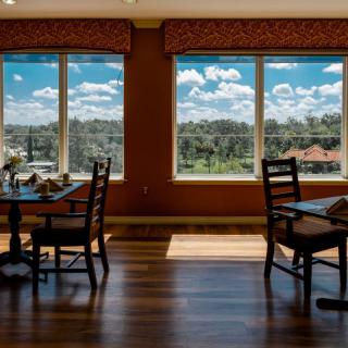 A well-lit dining room with large windows offering a scenic outdoor view.