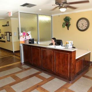 A reception area in an office with a wooden desk, wall clock, and ceiling fan.