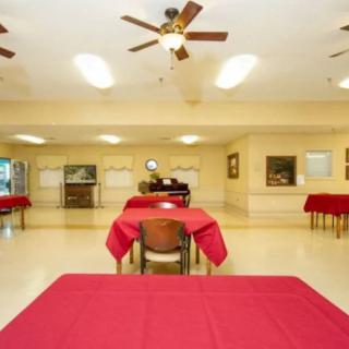 A spacious dining area with red tablecloth-covered tables and ceiling fans.