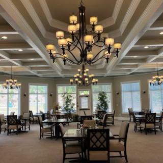 A spacious dining area with elegant chandeliers and large windows.