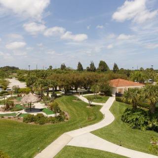 A scenic outdoor landscape with winding paths, lush greenery, and a house in the background.