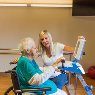 A caregiver assists an elderly individual in a rehabilitation session, fostering engagement and support.