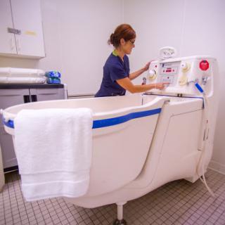 A healthcare professional prepares a hydrotherapy bath for patient treatment in a wellness facility.