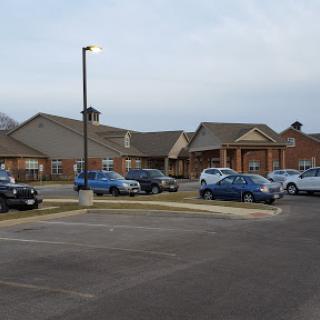 A view of a residential building with vehicles parked in the lot.