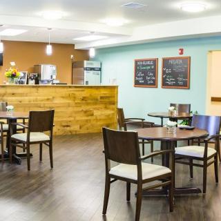 A cozy cafe interior with wooden tables and chairs, featuring a counter and menu boards.