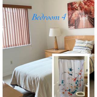 A cozy bedroom featuring a single bed, nightstand with a lamp, window blinds, and a decorative painting. An inset shows part of the bathroom decor with floral accents.