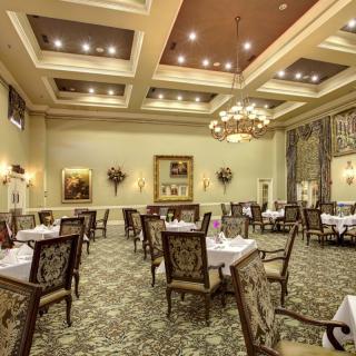 An elegant restaurant dining room with chandeliers and neatly arranged tables.