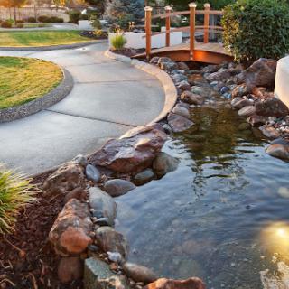 A serene garden featuring a winding path, a charming bridge, and a peaceful pond surrounded by rocks.