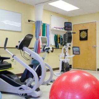 A fitness room equipped with exercise bikes, an exercise ball, and various gym equipment for therapy and rehabilitation.